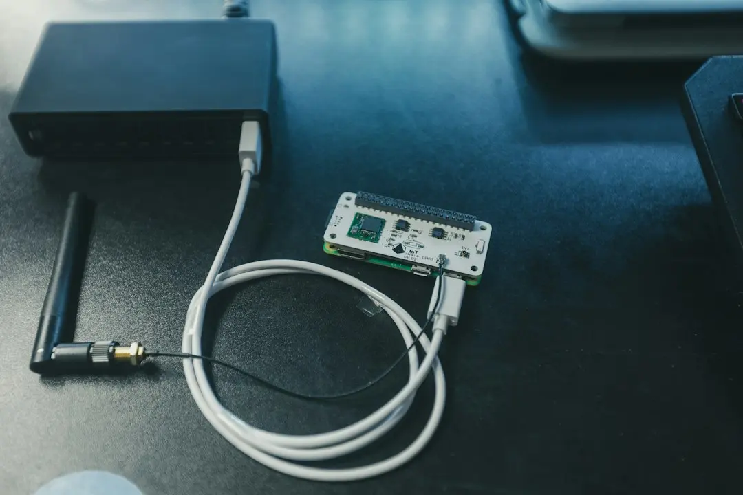 A network switch, antenna and small circuit board connected by white cables on a dark desk, the hardware that carries IPTV